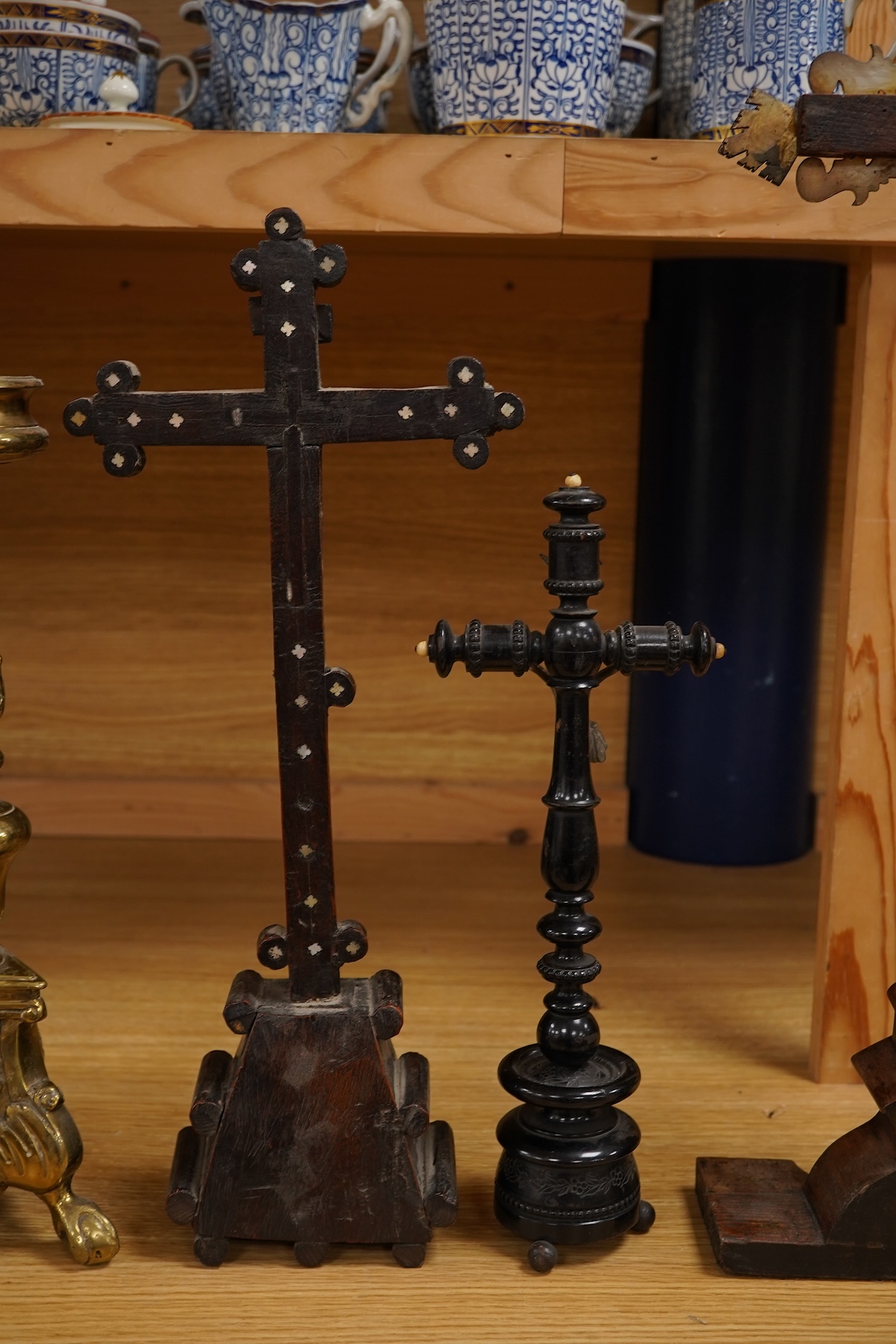 Two 19th century walnut and mother-of-pearl inlaid crucifixes and a German ebonised and white and metal mounted crucifix and a pair of Dutch or German brass tripod base cricket candlesticks, largest 56cm high (5)